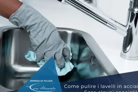Mano con guanto grigio pulisce lavello in acciaio con panno azzurro. Scopri come pulire il lavello in acciaio dal calcare.
