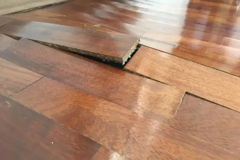 Parquet sollevato e deformato, con evidenti macchie di umidità che hanno compromesso le doghe.