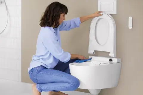 Donna pulisce il WC con un panno blu. Per una pulizia profonda, usa ammoniaca per pulire wc.
