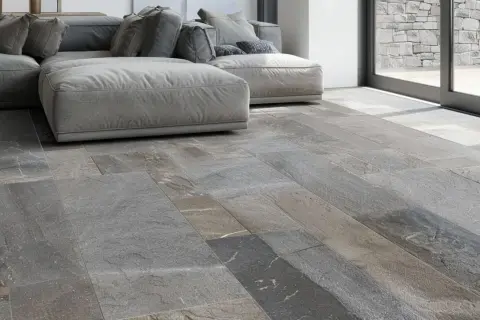 Pavimento in pietra di Luserna, grigio e variegato, con un divano moderno. Ideale per chi cerca consigli su come pulire la pietra di Luserna.