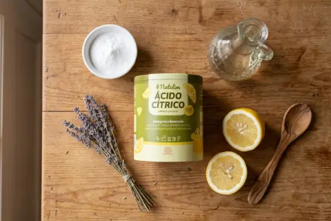 Ingredienti per un detersivo lavatrice fatto in casa: acido citrico, bicarbonato, lavanda, limoni e un cucchiaio di legno.