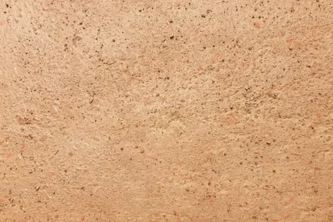 Dettaglio di un antico cocciopesto pavimento, con frammenti di terracotta e pietre che creano una texture rustica e calda.