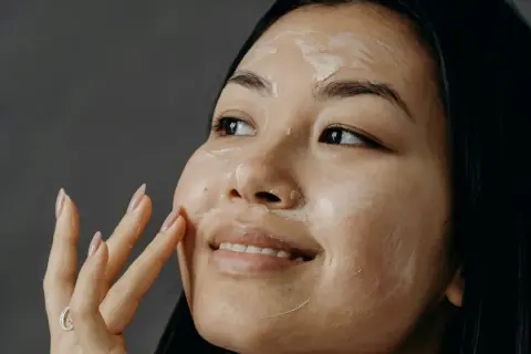 Donna applica una maschera sul viso, un gesto quotidiano per imparare come curare la pelle del viso e renderla luminosa.