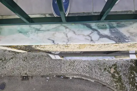 Come togliere la vernice dal marmo: una macchia verde su un davanzale di marmo, con scarpe blu in primo piano.