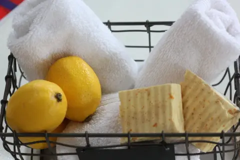 Cesto con sapone al limone fatto in casa, limoni freschi e morbidi asciugamani bianchi.