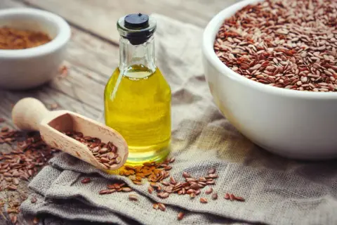 Olio di lino per pavimenti in graniglia, con semi sparsi e una ciotola piena.