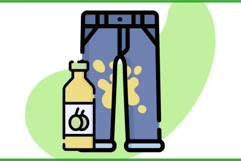 Un flacone di detersivo accanto a un paio di pantaloni con una macchia d'olio gialla.