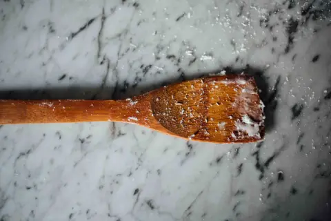 Un cucchiaio di legno con residui di sapone di Marsiglia, pronto per pulire pavimenti in marmo.