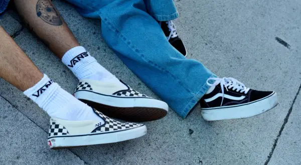 Due paia di Vans, una a scacchi e una nera con zeppa, pronte per essere lavate in lavatrice.