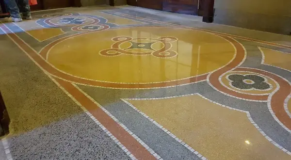 Pavimenti marmo anni 70 con motivi geometrici e floreali in giallo, grigio e rosso. Un restauro che riporta alla luce la bellezza del passato.