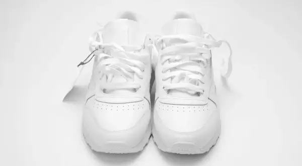 Un paio di scarpe da ginnastica bianche, nuove di zecca, con etichetta. Chissà a quanti gradi si lavano le scarpe per mantenerle così immacolate.