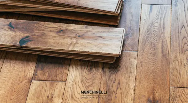 Tavole di parquet in legno grezzo, pronte per il trattamento. La venatura del legno è ben visibile, con nodi scuri che aggiungono carattere.