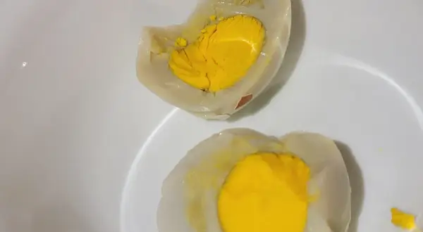Uova sode tagliate a metà in una ciotola bianca, con tuorli gialli brillanti. La puzza di uovo marcio in casa è innegabile.