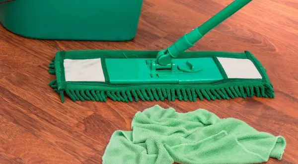 Mocio verde e secchio su pavimento in legno, pronti per pulire con ammoniaca per pavimenti.