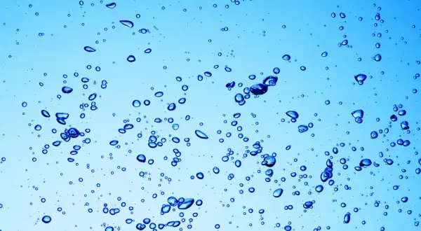 Bollicine blu in acqua chiara, un'immagine che ricorda a cosa serve l'acqua ossigenata: per pulire e disinfettare.