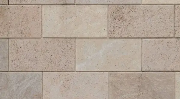 Dettaglio di un pavimento in trachite, con blocchi rettangolari di pietra chiara, alcuni con venature naturali e piccole inclusioni.