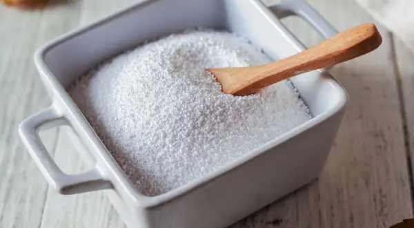 Perborato di sodio dove si compra? Granuli bianchi in una ciotola con un cucchiaio di legno, pronti per essere usati.