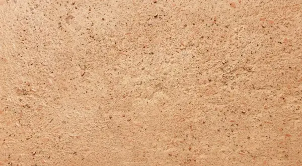 Dettaglio di un antico cocciopesto pavimento, con frammenti di terracotta e pietre che creano una texture rustica e calda.