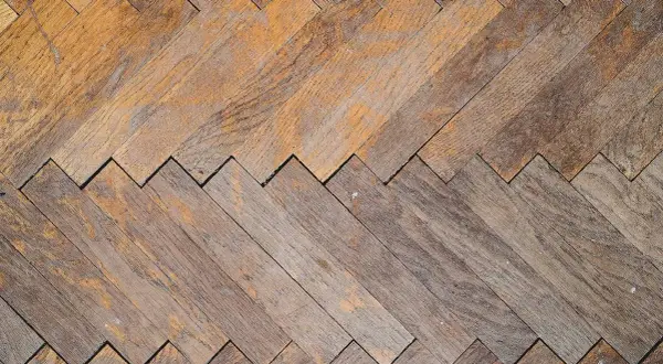 Parquet in legno con motivo a spina di pesce, usurato ma pronto per essere lucidato con rimedi della nonna per farlo brillare.