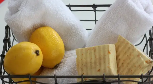 Cesto con sapone al limone fatto in casa, limoni freschi e morbidi asciugamani bianchi.