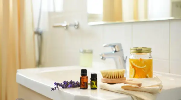 Lavanda, oli essenziali, spazzola e arance in barattolo sul lavandino. Un bagno pulito e profumato, non un bagno sporco.