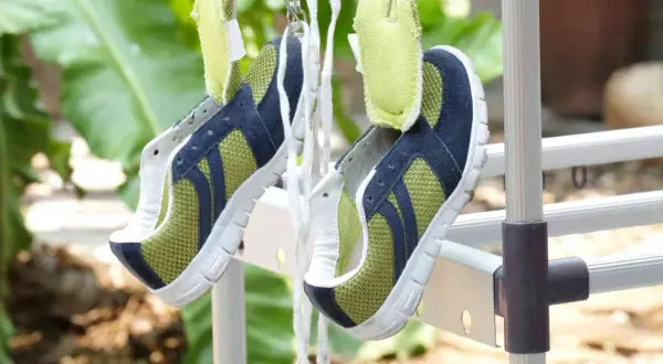 Scarpe sportive verdi e blu appese ad asciugare all'aperto, un metodo efficace per capire come lavare le scarpe dentro e farle tornare come nuove.