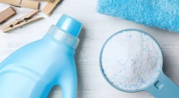 Detersivo in polvere in un misurino accanto a una bottiglia di detersivo liquido. Qual è meglio detersivo in polvere o liquido?