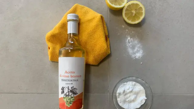 Aceto di vino bianco, bicarbonato, limoni e un panno giallo per lavare i pavimenti con aceto e ammorbidente.
