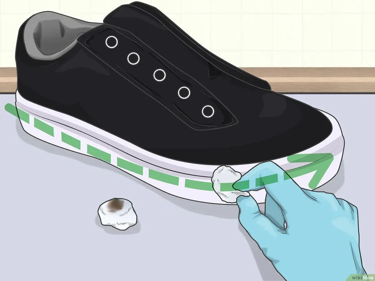 Guanto blu pulisce la suola bianca di una scarpa nera con un batuffolo di cotone. Ecco come pulire la suola delle scarpe per farle sembrare nuove.