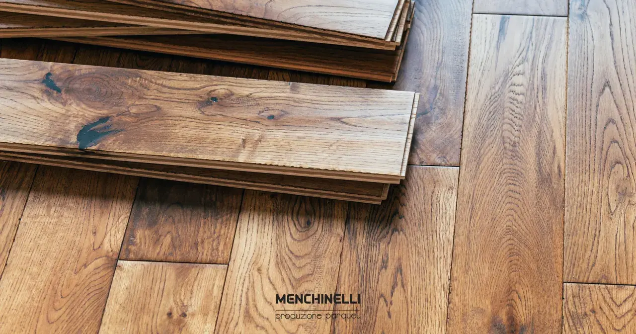 Tavole di parquet in legno grezzo, pronte per il trattamento. La venatura del legno è ben visibile, con nodi scuri che aggiungono carattere.