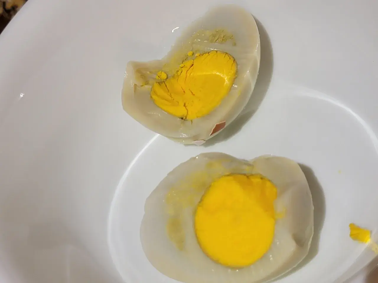 Uova sode tagliate a metà in una ciotola bianca, con tuorli gialli brillanti. La puzza di uovo marcio in casa è innegabile.