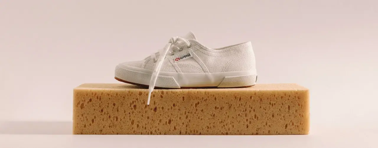 Scarpa bianca Superga su una spugna, pronta per lavare Superga in lavatrice.