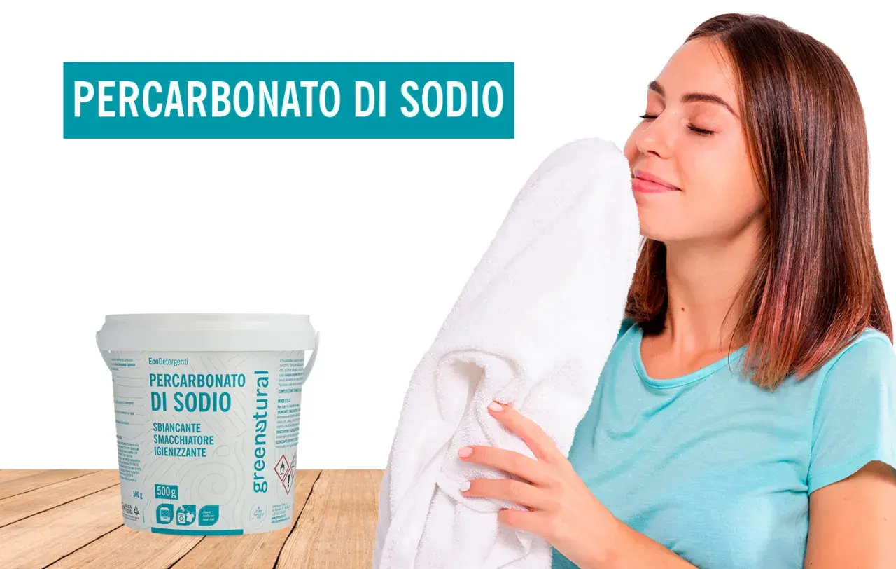 Donna annusa un candido asciugamano, felice del profumo fresco. Accanto, un barattolo di Percarbonato di Sodio, smacchiatore naturale per lavatrice.