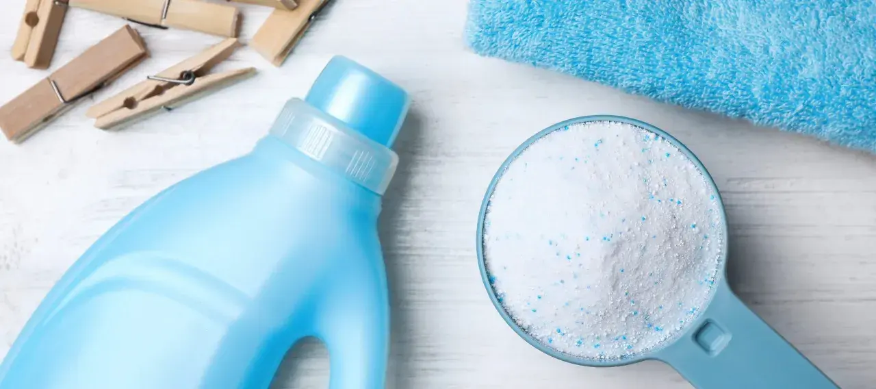 Detersivo in polvere in un misurino accanto a una bottiglia di detersivo liquido. Qual è meglio detersivo in polvere o liquido?