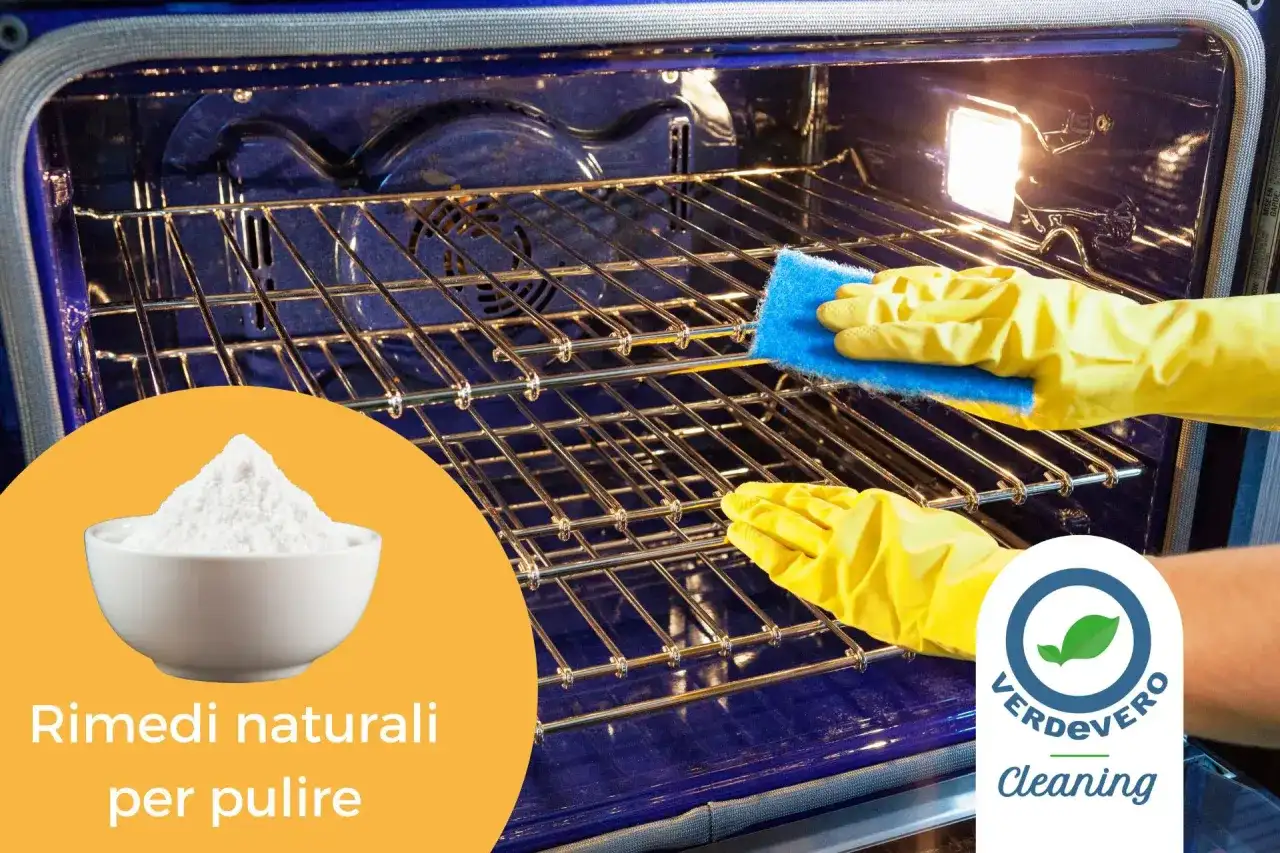 Mani con guanti gialli puliscono le griglie del forno con una spugna blu. Una ciotola di bicarbonato di sodio suggerisce come pulire il forno con prodotti naturali.