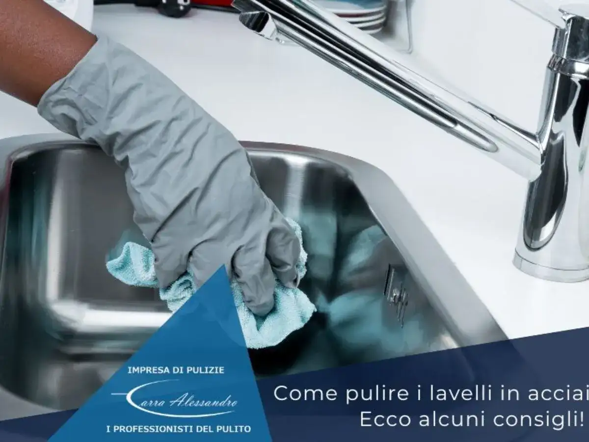 Mano con guanto grigio pulisce lavello in acciaio con panno azzurro. Scopri come pulire il lavello in acciaio dal calcare.