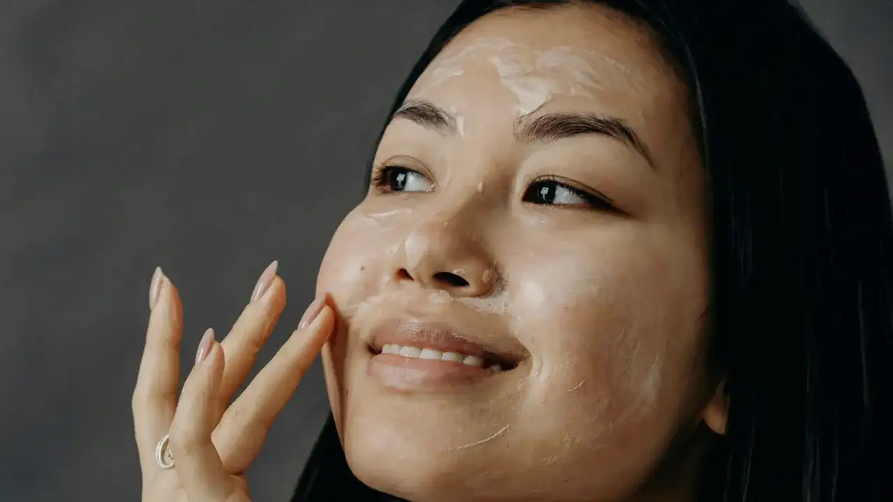 Donna applica una maschera sul viso, un gesto quotidiano per imparare come curare la pelle del viso e renderla luminosa.
