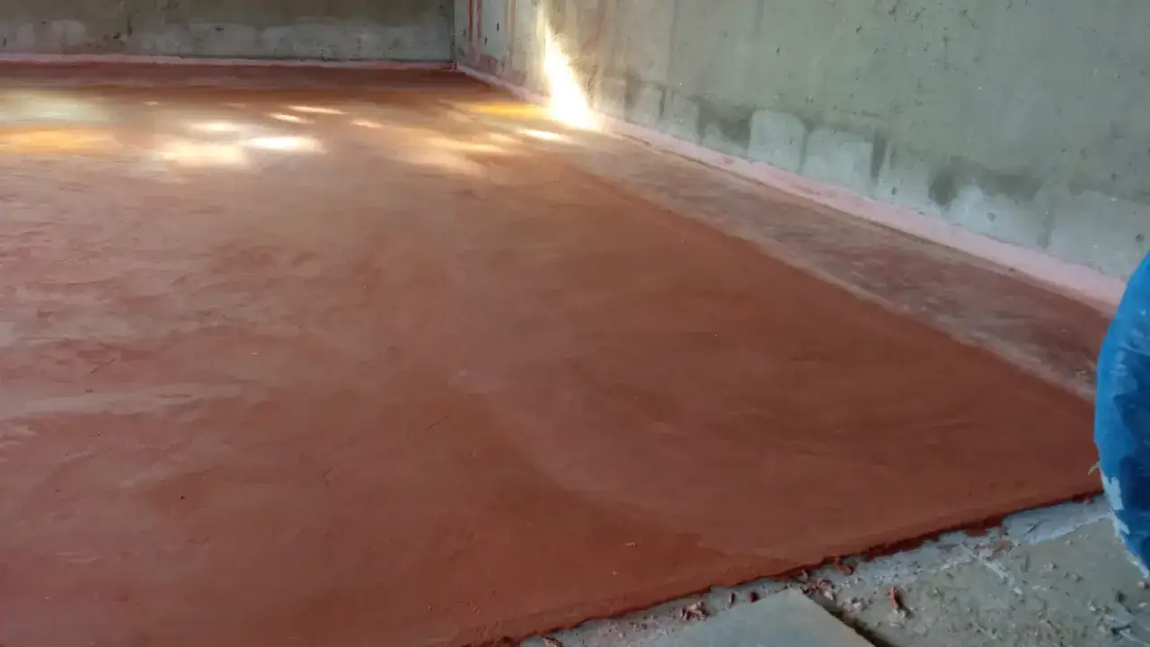 Un nuovo cocciopesto pavimento, rosso mattone, attende la luce del sole che filtra dalle finestre, creando un'atmosfera calda e accogliente.
