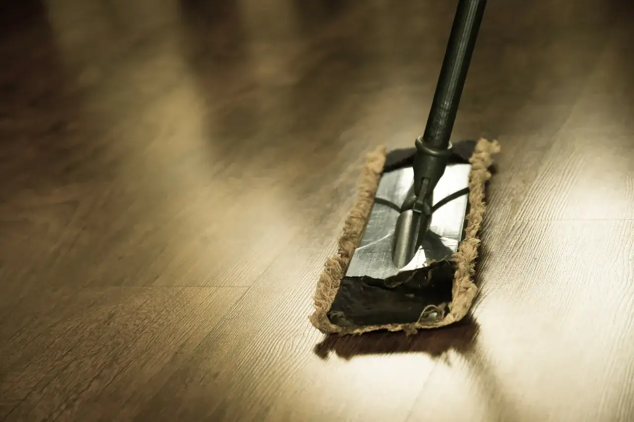 Un mocio pulisce un parquet lucido. Un metodo ecologico per lavare parquet con aceto e bicarbonato per una casa splendente.