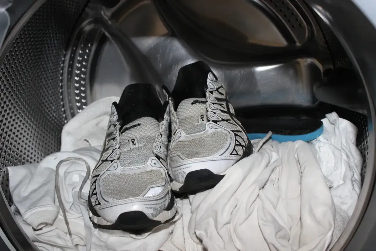 Scarpe da ginnastica pronte per essere lavate in lavatrice, con asciugamani bianchi. Ecco come lavare le scarpe in lavatrice per farle tornare come nuove.