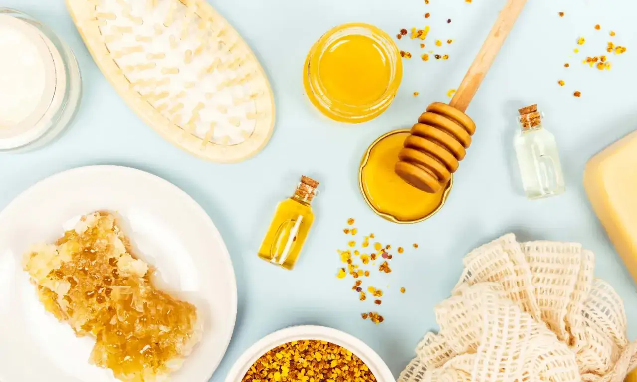 Prodotti naturali per capelli secchi: miele, cera d'api, oli essenziali e spazzola.