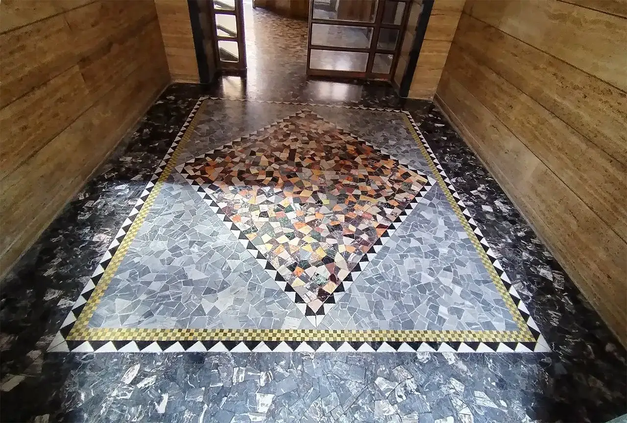 Un prezioso bollettonato di marmo con un motivo a rombo centrale colorato e bordi geometrici.