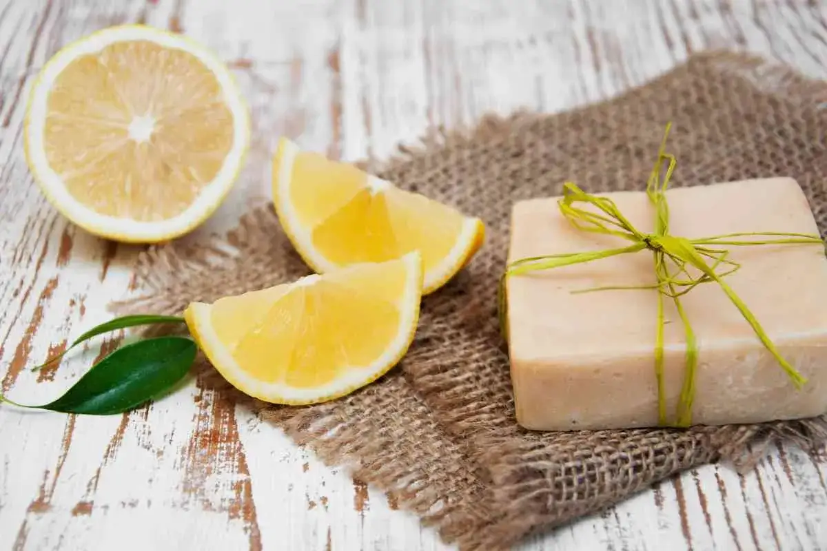 Un sapone al limone fatto in casa, con fette di limone fresco e una foglia verde su un tavolo di legno rustico.