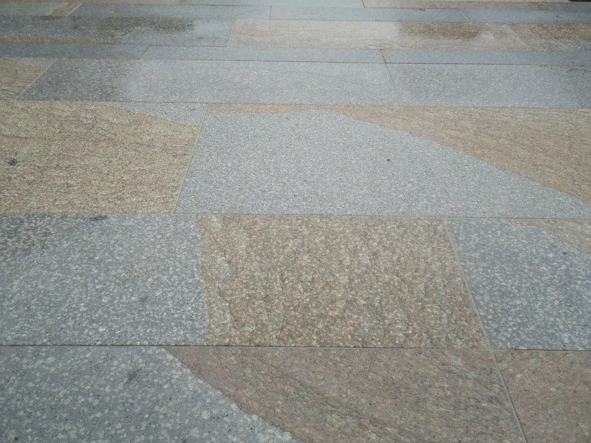 Un elegante pavimento in trachite grigia e ocra, con lastre di diverse dimensioni che creano un motivo geometrico moderno.