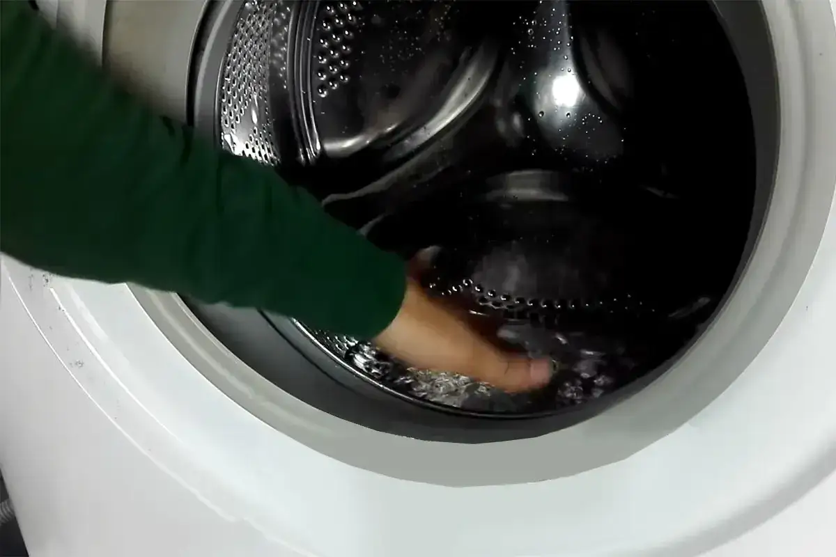 Mano in lavatrice per capire come togliere l'acqua residua.