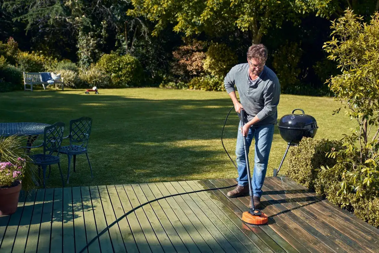Uomo pulisce il terrazzo esterno con idropulitrice, mostrando come pulire terrazzo esterno in modo efficace.