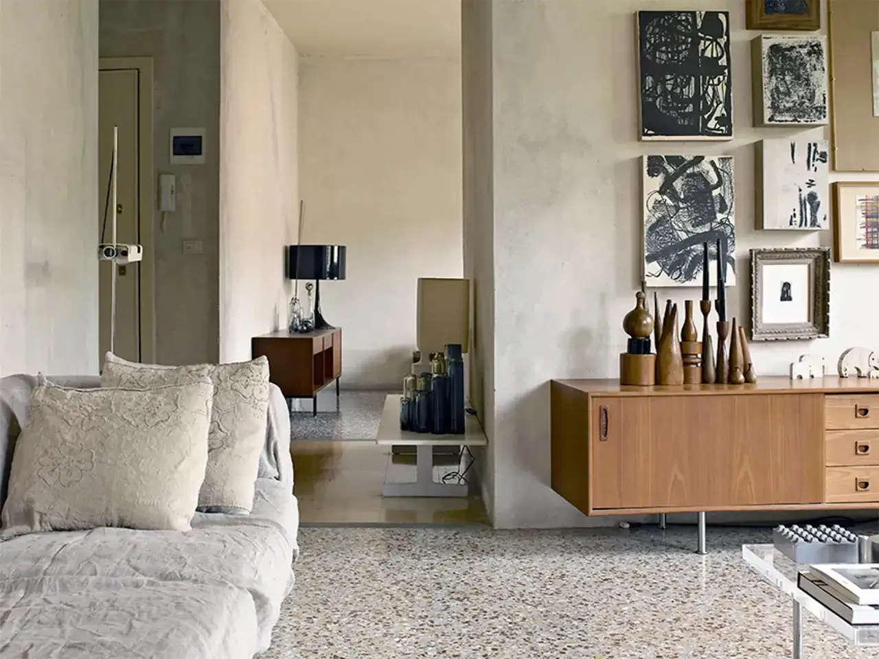 Un soggiorno con divano grigio, quadri astratti e un mobile in legno su un elegante pavimento scaglietta.