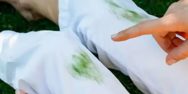 Un dito indica delle macchie d'erba su pantaloni bianchi, un piccolo disastro dopo una giornata all'aperto.