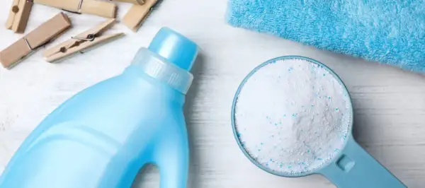 Detersivo in polvere in un misurino accanto a una bottiglia di detersivo liquido. Qual è meglio detersivo in polvere o liquido?